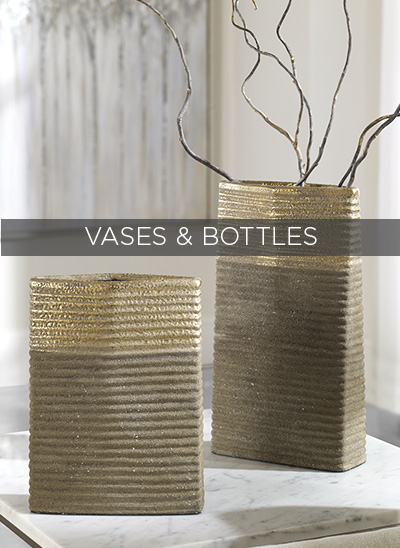 Two vases and bottles on a table.