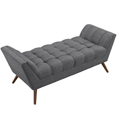A grey upholstered bench with wooden legs.