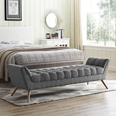 A grey upholstered bench in a bedroom.