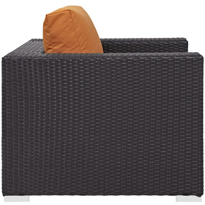 An outdoor wicker lounge chair with orange cushion.