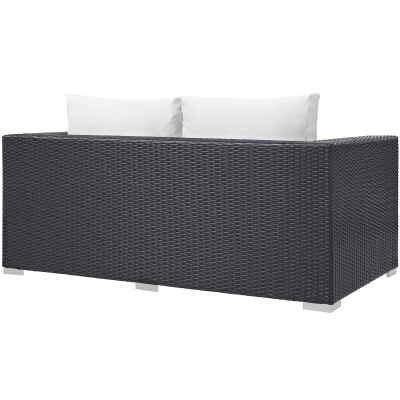 A black wicker sofa with white pillows.