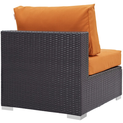 An outdoor wicker chair with orange cushions.