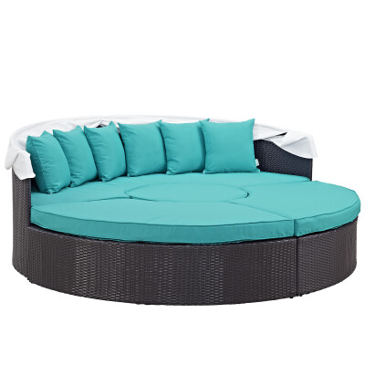 A round rattan daybed with turquoise cushions.