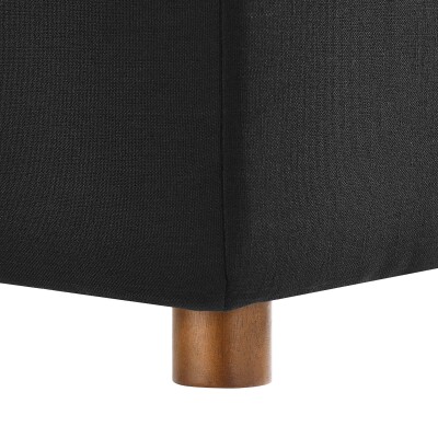 A black ottoman with wooden legs on a white background.