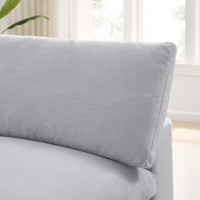 The back of a grey couch with a pillow on it.