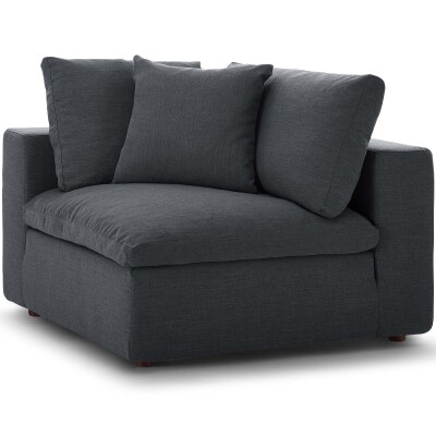 A grey corner chair with pillows on it.