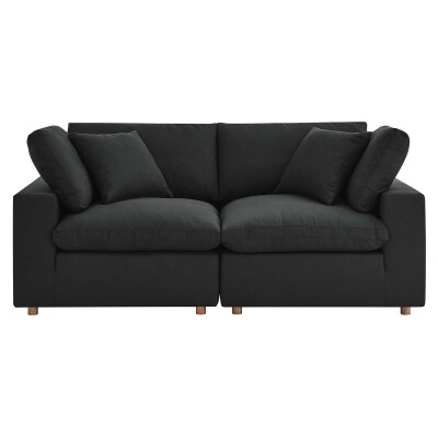 A black sofa with two pillows on it.