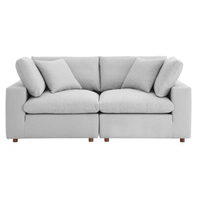 A light grey sofa with pillows on it.