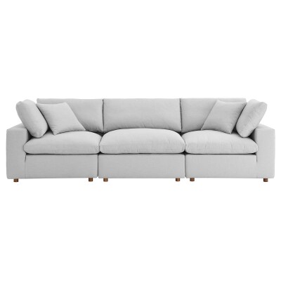 A white sectional sofa with pillows on it.