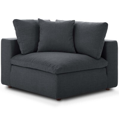 A grey corner chair with pillows on it.