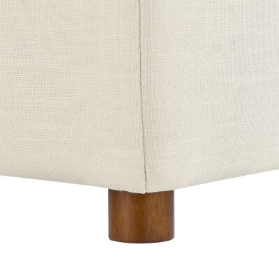 A close up of a beige couch with wooden legs.